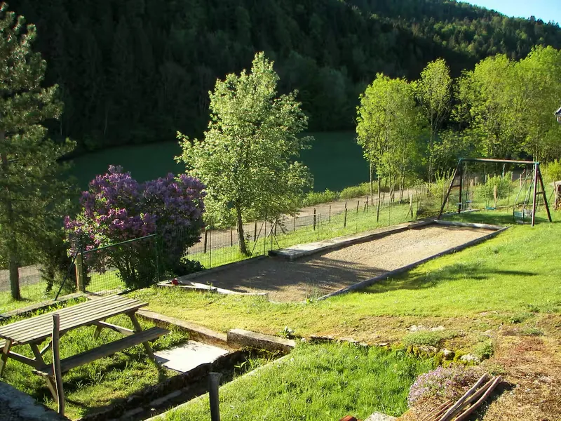Le terrain de pétanque et la table de jardin, avec le lac en contrebas